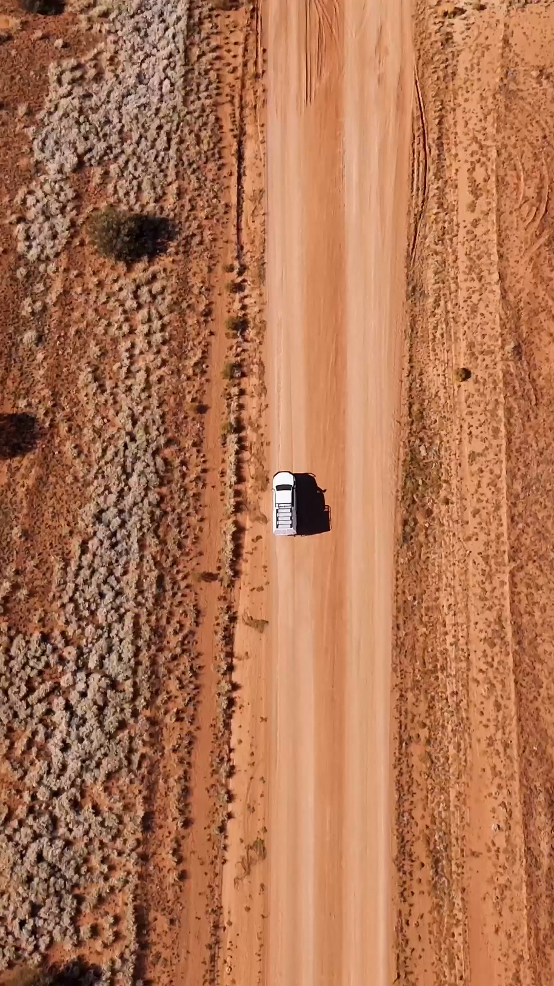 An aerial view of a vehicle travelling along a red earth road, from the NPY Women’s Council reel